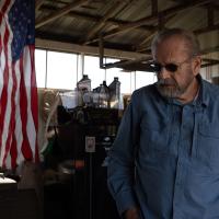 Howard Galbreath stands in one of the work sheds on his property in Owento, Ky. An American flag is draped from the ceiling, to his immediate right.