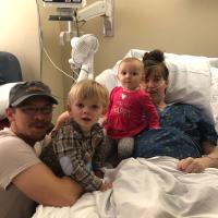 The Custer family sitting in a hospital bed.