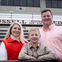 From left: Brittany Dean, William Dean and Tyler Dean standing in the bleachers of a football stadium