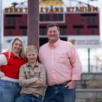 Brittany Dean, Wiliam Dean and Tyler Dean stand in front of the scoreboard at Russell's football stadium.