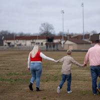 Brittany Dean, William Dean and Tyler Dean walk together on a football field