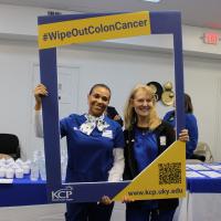 UK HealthCare team members pose with a large photo frame that reads #WipeOutColonCancer.