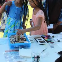 Two preteen girls select rubber stamps at an arts-and-crafts table at the event.