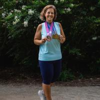 Wide portrait of Jeanne Hartman, who proudly displays her running medals post weight loss surgery