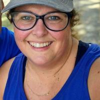 Jeanne Hartman smiles at a camera, wearing a blue tank top and a classic Kentucky Wildcats logo hat, prior to weight loss