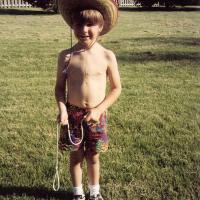 A scanned photo of Dr. Kyle Riggs as an elementary-age kids. He's dressed in a summer bucket hat and shorts.