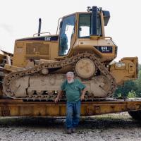 Wide shot of Shorty Carson leaning on his bulldozer