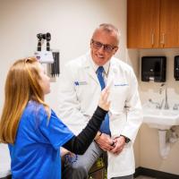 Dr. Scottie Day consulting with a young patient who's seated in an exam room
