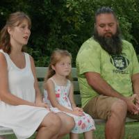 Jamie Newton, Izzy Newton and Joshua Newton sit on a park bench while looking off camera