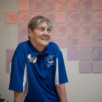 Sallie Wilson smiling to someone off camera against a donor wall located at UK HealthCare