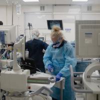 Medical professionals in a room crowded with devices and equipment during a procedure