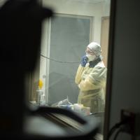 A medical provider makes a call, foreground out of focus, as we see them through glass