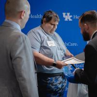 Jason holds a certificate and is mingling with men in suits