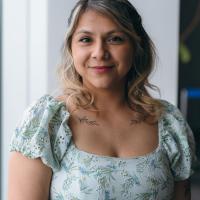 Maria Fuentes poses for a camera. She's wearing a floral dress.