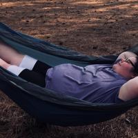 A candid photo of Abby laying in a hammock with her arms behind her head.