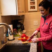 Amberlee cuts up a red bell pepper in her kitchen.
