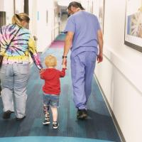 Arlo Yost is walking between his mother and Dr. Talwalkar, holding their hands as they make their way down the hallway.