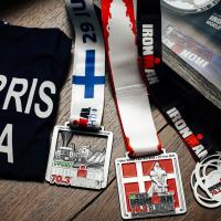Several IRONMAN medals and mementoes of past races sit on a table.