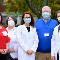 Dr Bensalem-Owen and four members of her team—three middle-aged white women and a middle aged white man—are standing in an outside area setting with their facemasks on.