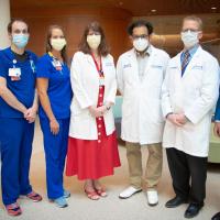 A group of doctors, nurses and therapists stand in a line formation for a portrait photo.