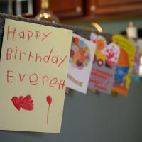 A close-up of a handmade card that reads “Happy Birthday Everett.” It is one of many cards taped to the counter.