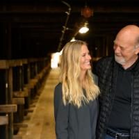 Fred and DeeAnn smile at each other while embracing inside of the barrel aging warehouse.