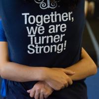 Photo features the back of a navy blue t-shirt that supports Turner Syndrome with the text “Together, We Are Turner Strong!”