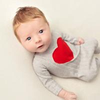 A close-up of Jeremiah as an infant. He’s looking up at the camera, while wearing a onesie that has a large red heart sewn onto it.