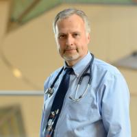 Dr. Stefan Kiessling, a middle-aged white man with grey hair, stands in the lobby of Kentucky Children’s Hospital wearing a light blue shirt, with a navy-blue tie and a stethoscope placed around his neck.