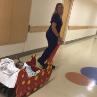 A candid photo of one of Kailey’s nurses looking back over her shoulder as she pulls Kailey down the hallway in the Brady Buggy.