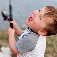 Kase laughs gleefully while holding a fishing pole.