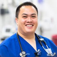 Khay smiles while wearing his blue UK HealthCare nursing scrubs.
