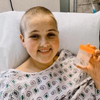 Kylee Tyson, having lost her hair during chemotherapy, smiles while receiving treatment
