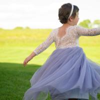 A photo of Leorah from behind as she twirls in an open field, her arms extended.