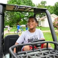 A candid photo of Malakai riding a small motorized cart around his neighborhood.