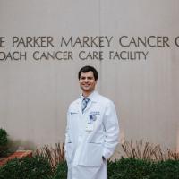 Marshall stands in front of the Lucille Parker Markey Cancer Center with his hands in his coat pocket, smiling broadly.