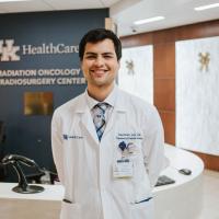 Marshall standing in the UK HealthCare Radiation Oncology and Radiosurgery Center. He is wearing a white doctor’s coat and a blue plaid tie.