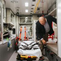 A candid photo of Matt standing over the gurney as he moves around the ambulance.