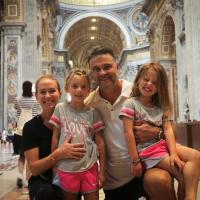 Matthew Mitchell and his wife and two daughters smile for a family photo in an ornate cathedral.