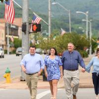 Michael, his wife, Diane, and their two grown children walking down the sidewalk together in the town of Middlesboro.