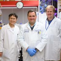 Dr. D’Orazio, Dr. Pu, and Dr. Holcomb smile as they pose for the camera in their lab.