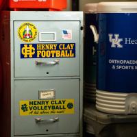 An old, light blue filing cabinet has an assortment of Henry Clay athletic bumper stickers on it. Next to it is a blue UK HealthCare Orthopaedic Surgery &amp; Sports Medicine water cooler.