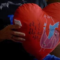 A close-up photo of Andy holding a heart-shaped pillow that has a signed message on it.
