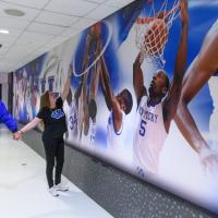 A photo of Andy and Julie holding hands as they admire the wall decal of UK basketball players.