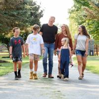Dr. Day and his family walk down the driveway of their house together as they all smile while looking towards Dr. Day.