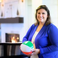 A photo of Dr. Rhodus in her office smiling as she holds a beach ball.