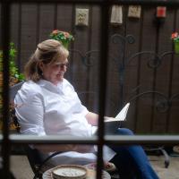 Suzanne relaxes in a chair outside and reads a book.