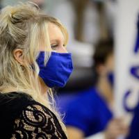 A close-up photo of Dr. Kaiser wearing a mask and looking off-camera as she watches the UK cheerleaders perform.