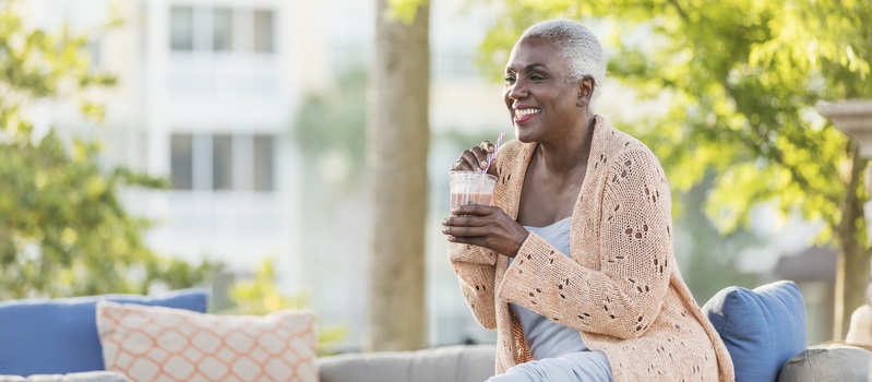 Woman drinks a smoothie while relaxing outside on a couch.