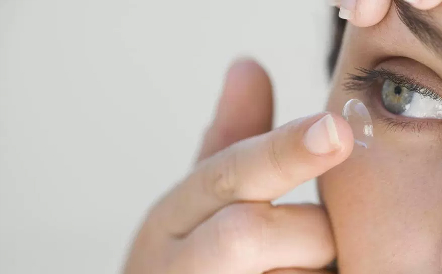 A woman inserts a contact lens.